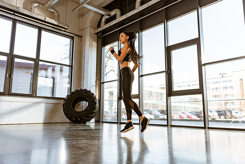 Brunette sportswoman in sportswear jumping in sports center