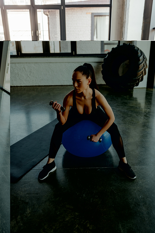 Sexy sportswoman with dumbbells looking away on fitness ball near fitness mat in gym
