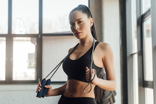 Beautiful sportswoman holding skipping rope and  in gym