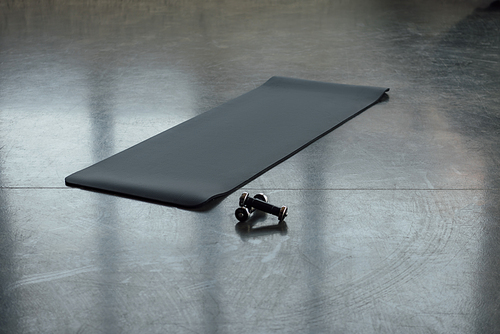 Fitness mat with dumbbells on floor in sports center
