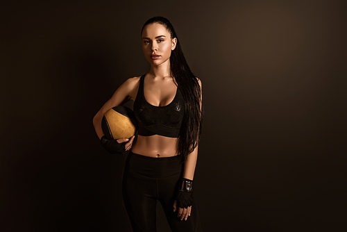 Brunette sportswoman with ball  isolated on black