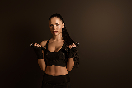 Sportswoman training with dumbbells and  isolated on black