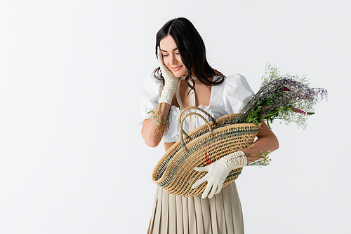 sensual young woman holding straw bag with spring flowers isolated on white