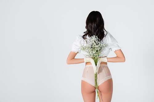 back view of brunette woman in gloves and panties with blooming flowers posing isolated on white