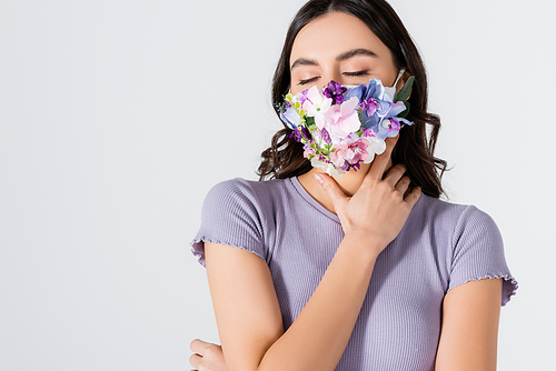 young model in crop top and medical mask with blooming flowers posing isolated on white