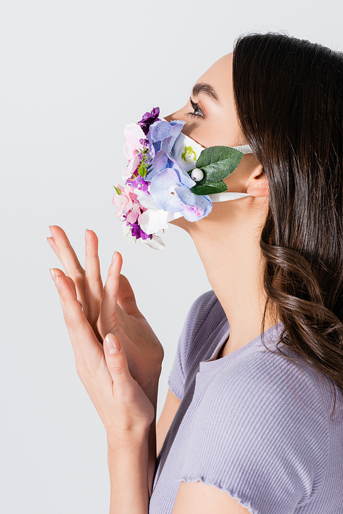 young woman in medical mask with flowers gesturing isolated on white