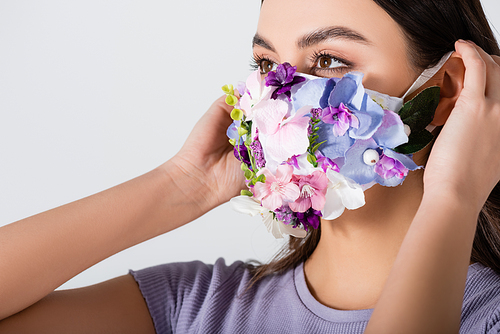 young woman wearing medical mask with blooming flowers isolated on white