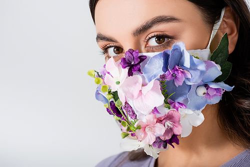 young woman in medical mask with blooming flowers isolated on white