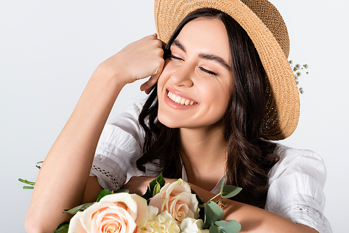happy woman in straw hat holding bouquet of spring flowers isolated on white