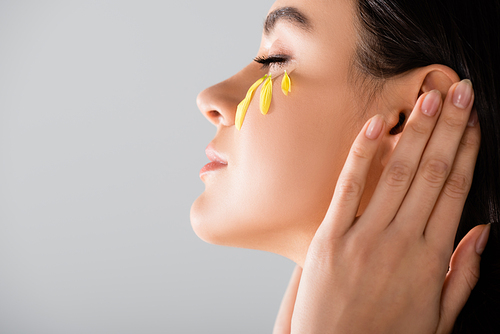 side view of young woman with yellow petals on face isolated on white