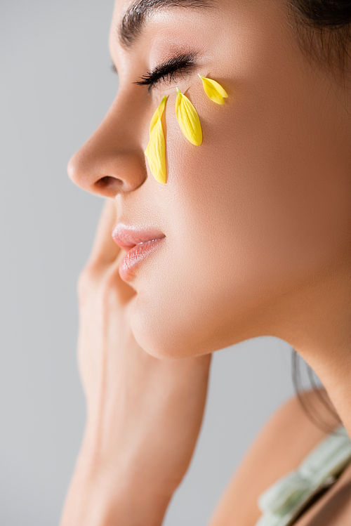 close up of young woman with yellow petals on face isolated on white