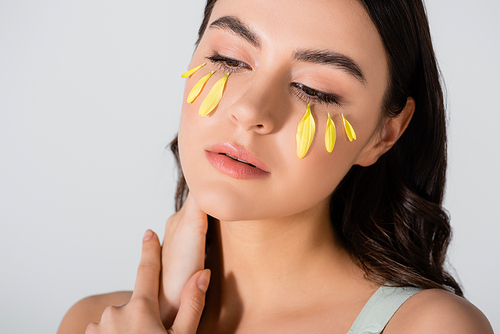 pensive young woman with yellow petals on face isolated on white