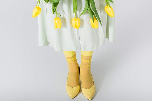 cropped view of woman in skirt with yellow tulips isolated on white