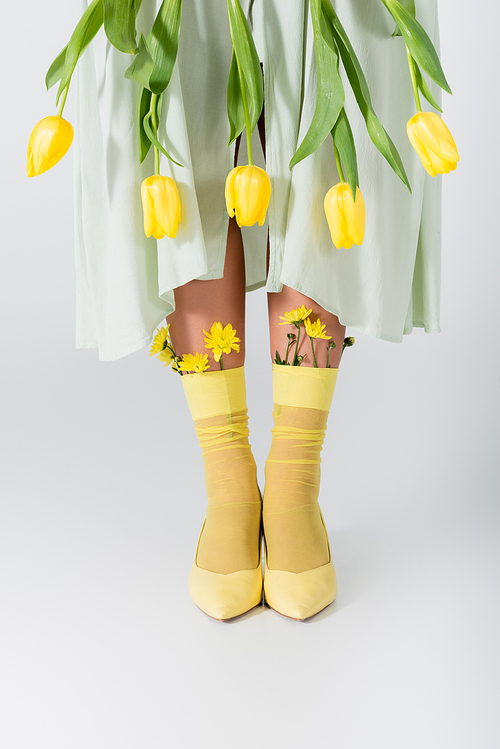 partial view of woman in skirt with yellow tulips isolated on white