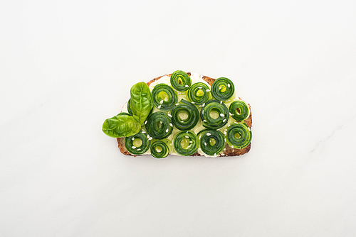 top view of fresh cucumber toast with basil leaves on white background