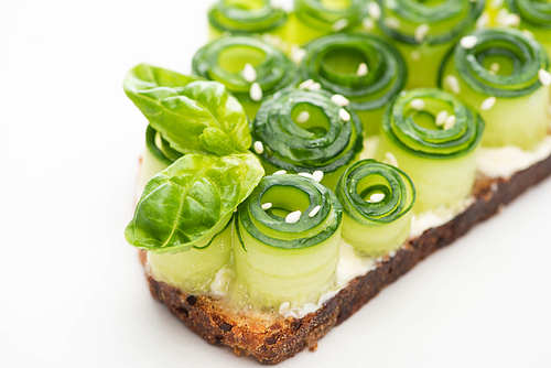 close up view of fresh cucumber toast with basil leaves and sesame on white background