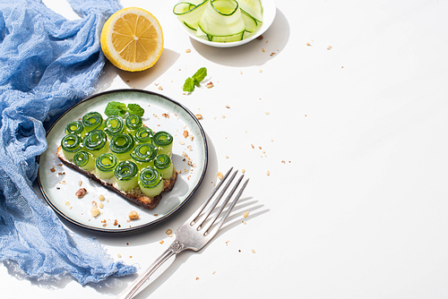 fresh cucumber toast with sesame, mint leaves near fork and lemon on white background