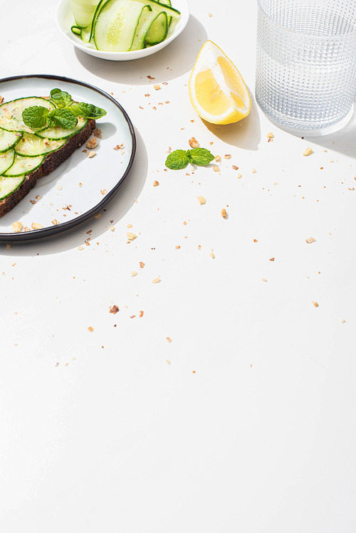 fresh cucumber toast with seeds served with lemon and water on white background