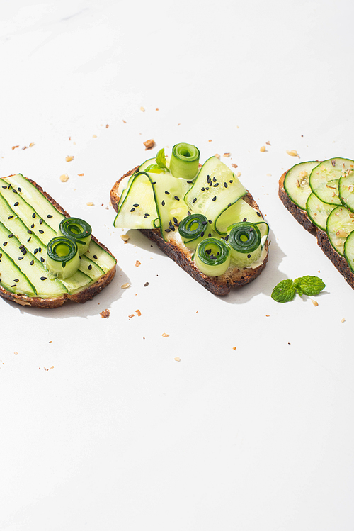 fresh cucumber toasts with seeds, mint leaves on white background