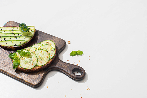 fresh cucumber toasts on wooden cutting board on white background
