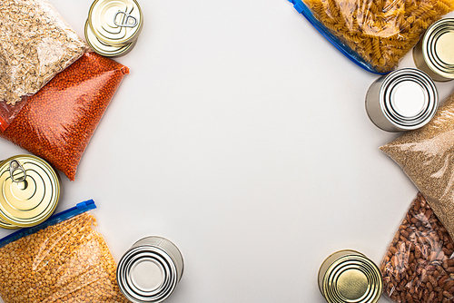 top view of cans and groats in zipper bags on white background, food donation concept