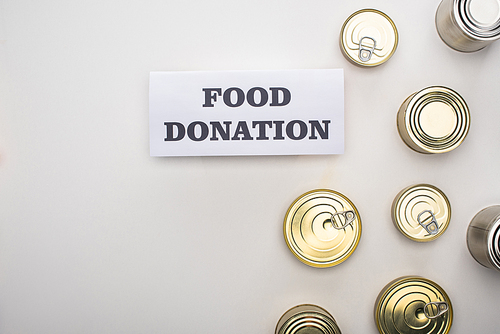 top view of cans near card with food donation lettering on white background