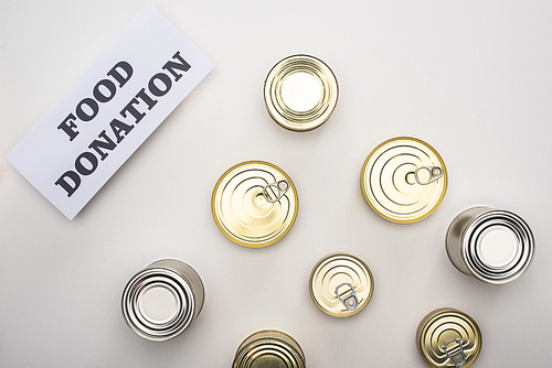 top view of cans with canned food on white background with food donation card