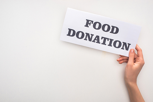 cropped view of woman holding card with food donation lettering on white background