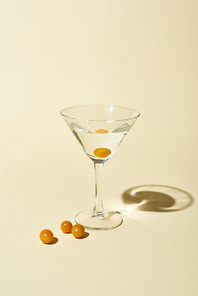 transparent glass with cocktail and berries on beige background