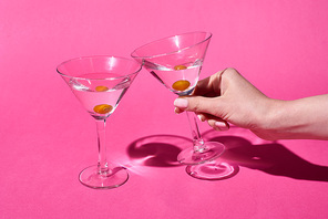 cropped view of woman holding glass of cocktail on pink background