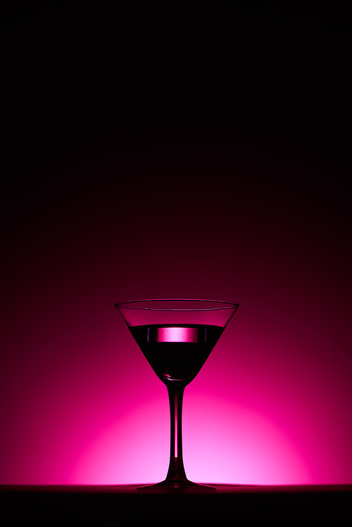 transparent glass with cocktail on pink background with back light