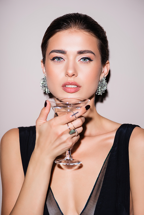 brunette woman holding glass of martini on white
