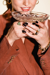 cropped view of happy woman in brown blazer drinking champagne from glass on white