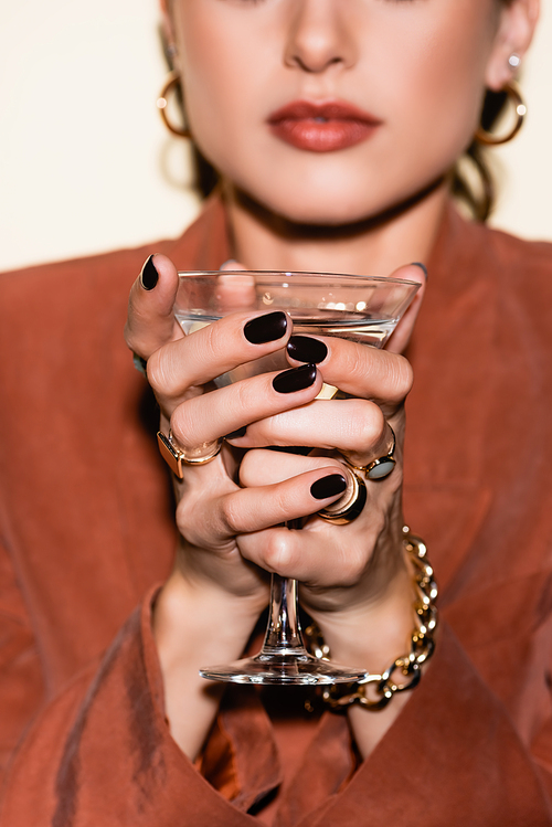 glass of alcohol drink in hands of woman in blurred background