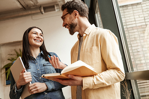low angle view of bearded man holding notebook while talking with cheerful woman