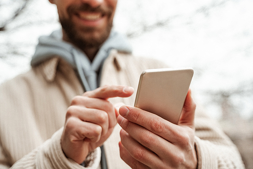 cropped view of bearded man pointing with finger at smartphone