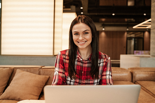 joyful woman smiling near laptop in cafe