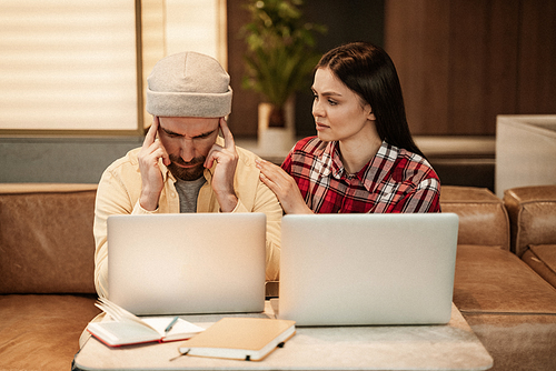 woman calming stressed bearded freelancer near laptops
