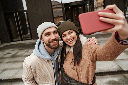 high angle view of happy couple in beanie hats taking selfie