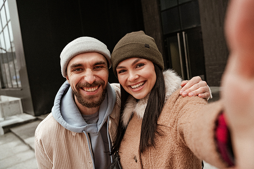 cheerful couple in beanie hats smiling at camera