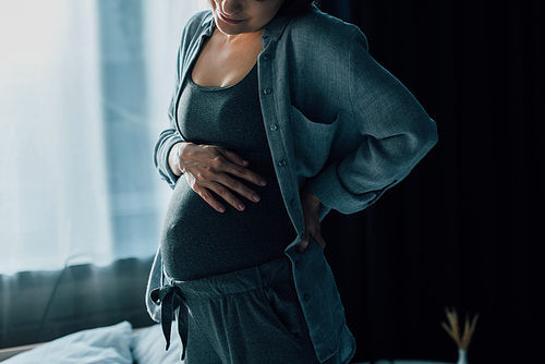 cropped view of pregnant woman suffering from pain and touching belly