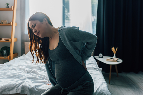 pregnant woman having back pain in bedroom