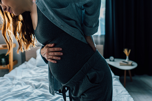 cropped view of pregnant woman having back pain in bedroom