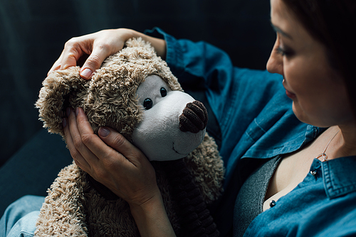 selective focus of depressed woman holding teddy bear