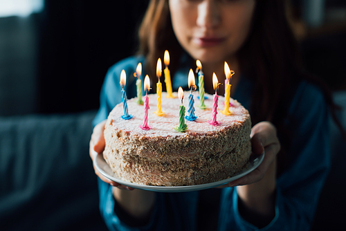 selective focus of sad woman holding birthday cake with candles
