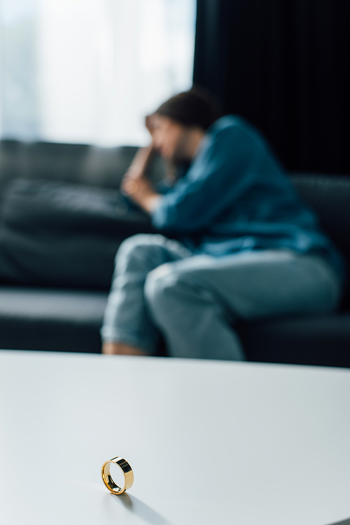 selective focus of golden ring on coffee table near woman, divorce concept