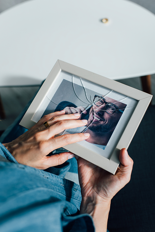cropped view of woman holding photo of husband with broken glass, divorce concept