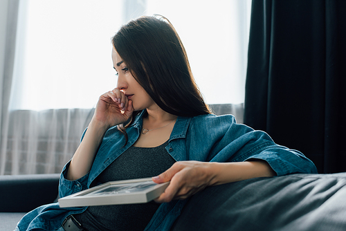 selective focus of upset woman holding photo with broken glass in frame, divorce concept