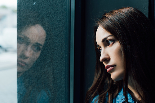 depressed and brunette woman looking at window