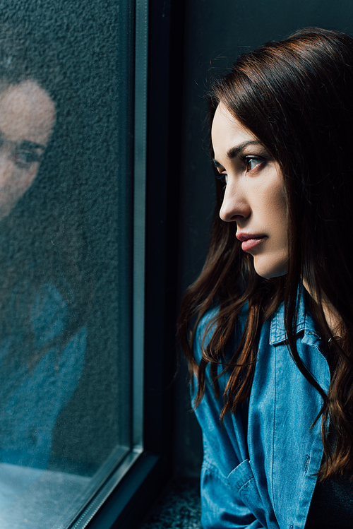 lonely and brunette woman looking at window